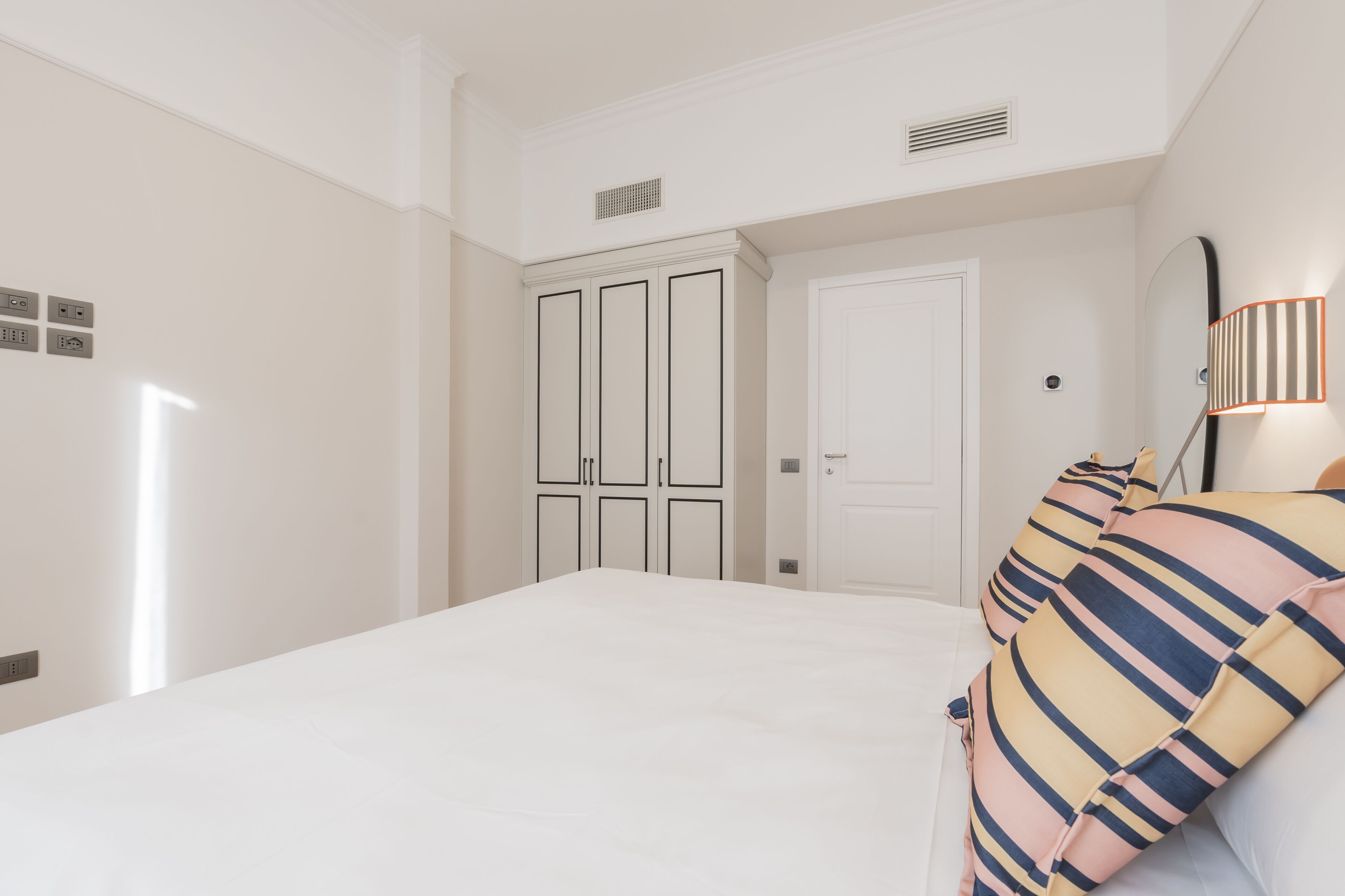 A bedroom with a large bed, a wardrobe, and a door.