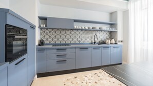 A modern kitchen with grey cabinetry, a patterned backsplash, and a black countertop. - Be Mate Trastevere II (Rome)