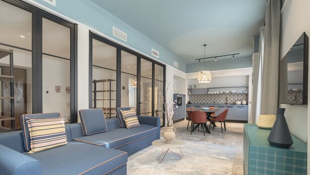 A modern living room with a blue sofa, a dining area with a table and chairs, and a kitchen in the background. - Be Mate Trastevere II (Rome)