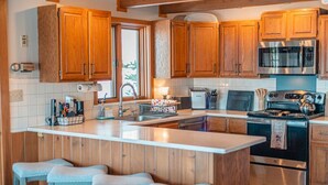 Una cocina moderna con armarios de madera, electrodomésticos de acero inoxidable y una isla central con taburetes de bar.