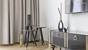 A modern living room with a black entertainment unit, a round glass table, and a decorative vase. - WelHome - Incredible Waterfront Apt With Mesmerizing views (Dubai)