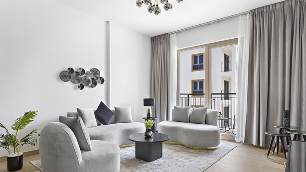 A modern living room with grey sofas, a round coffee table, and a potted plant. - WelHome - Incredible Waterfront Apt With Mesmerizing views (Dubai)