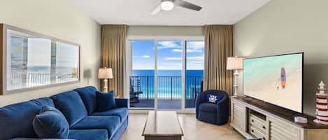 A hotel room with a balcony, a sofa, a TV, and a small table.
