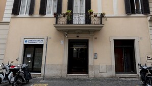 A multi-story building with a clinic on the ground floor, balconies with plants, and parked motorcycles. - Be Mate Trastevere III (Rome)
