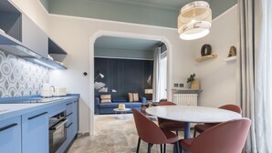 A modern kitchen with blue cabinets, a round dining table with red chairs, and a large window. - Be Mate Trastevere III (Rome)