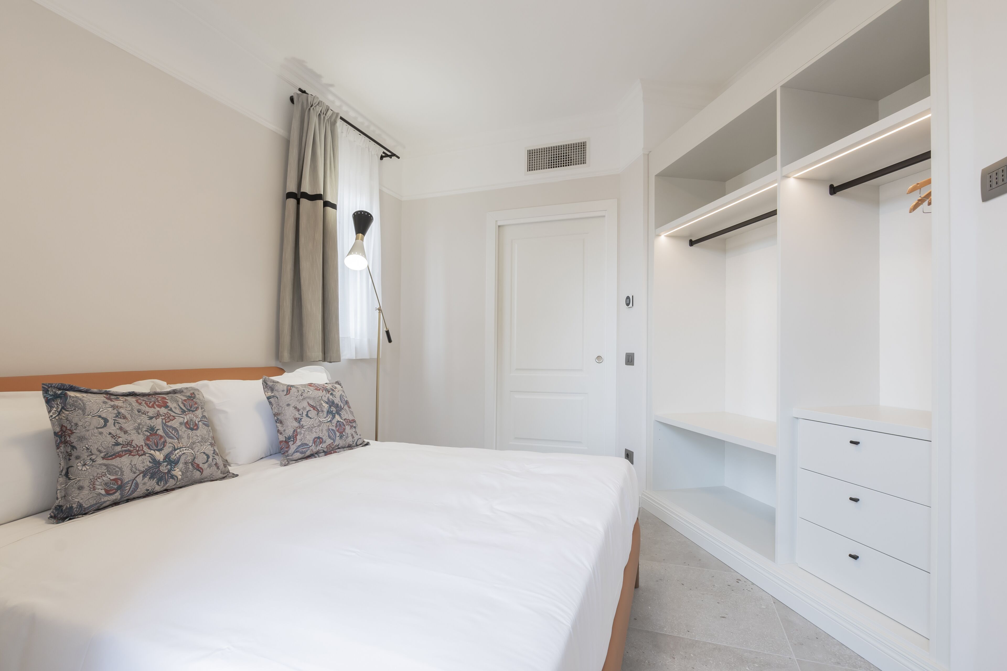 A bedroom with a bed, a wardrobe, and a nightstand.