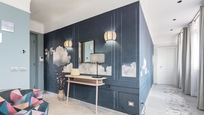 A modern hotel lobby with a geometric-patterned sofa, a console table with a lamp, and a wall with cloud-themed decorations. - Be Mate Trastevere III (Rome)