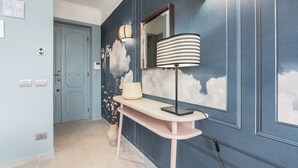 A hallway with a light blue door, a console table with a lamp, and a wall with cloud-themed decorations. - Be Mate Trastevere III (Rome)