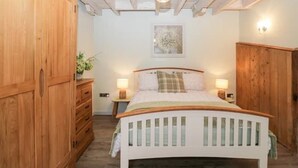 A bedroom with a wooden wardrobe, a bed with a white headboard, and two bedside lamps.