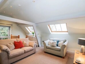 A spacious loft bedroom with a high ceiling, skylights, a large window, a sofa, a chair, and a bedside table. - Sleeps 5 plus a child, fantastic location to visit Malvern and Worcester. (WORCESTER)