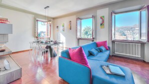 A modern living room with a blue sofa, dining table, and chairs. - Anita Lake, 2BR Retreat w/ Shared Pool and Gym (Gemonio)