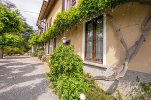 A building with a stone facade, multiple windows, and hanging plants.