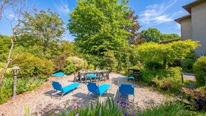 A patio area with outdoor seating, a pergola, and a large tree providing shade. - Anita Lake, 2BR Retreat w/ Shared Pool and Gym (Gemonio)