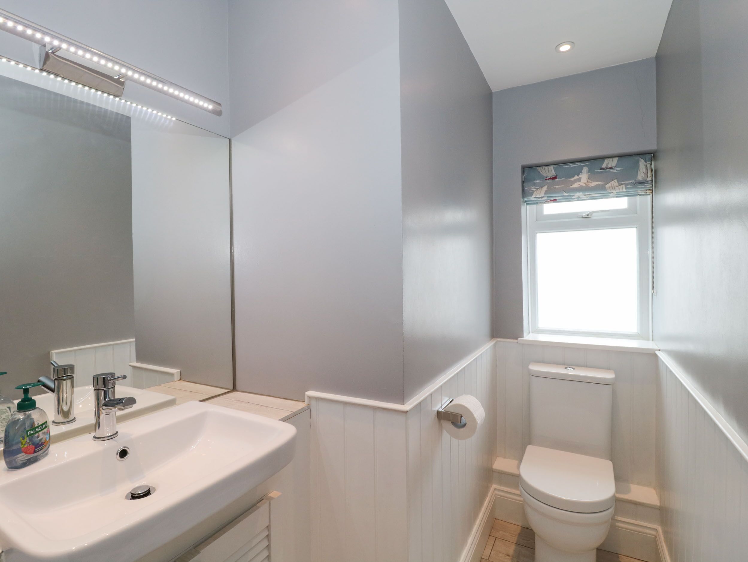 A bathroom with a white sink, mirror, and toilet.
