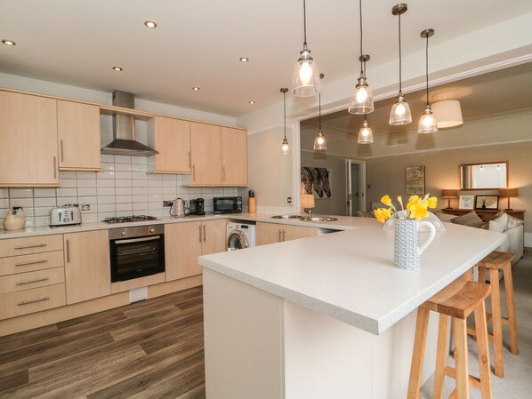 A modern kitchen with wooden cabinets, a central island, and pendant lighting.