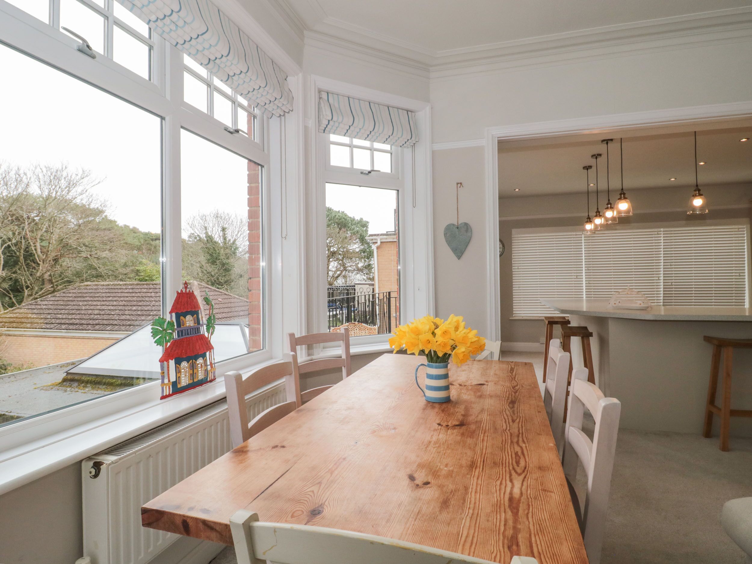 A dining area with a wooden table, white chairs, and a view of the outside.