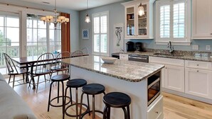 Une cuisine spacieuse dotée d’un grand îlot central, de meubles blancs et d’un coin repas avec une table et des chaises.