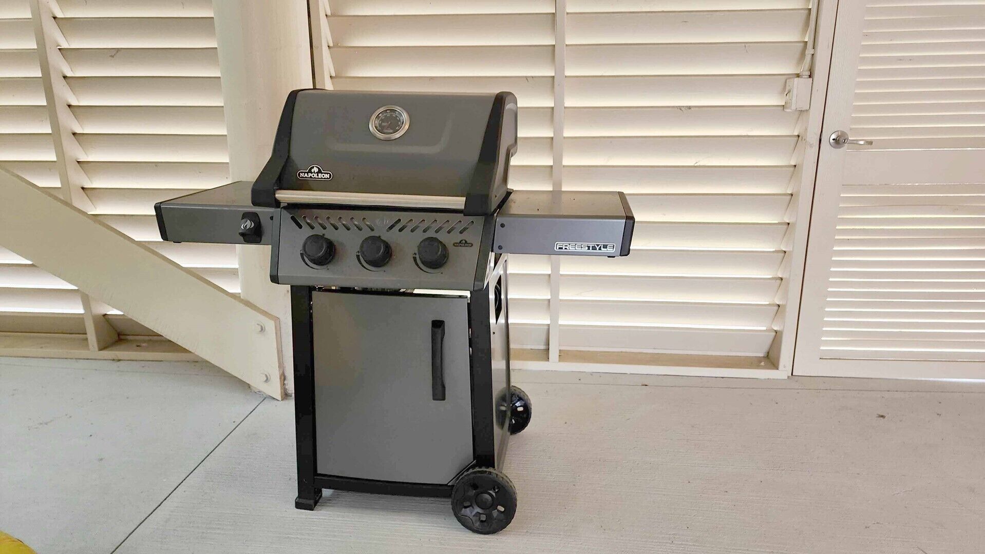 Een draagbare barbecue met bedieningspaneel en een extra brander, staand op een betonnen vloer.