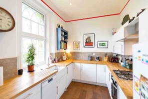 Enjoy cooking in this well-equipped kitchen with a potted plant on the windowsill and ample countertop space.
