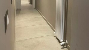Un couloir avec un radiateur, une porte et un luminaire.