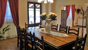 Un comedor con una mesa de madera, sillas, un florero y una araña.