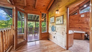 Ein Holzblockbau-Innenraum mit Holzboden, einem Badezimmer mit Waschbecken und Toilette sowie gerahmten Bildern an der Wand.