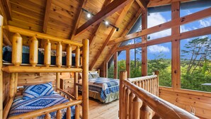 Eine Holzhütte mit Schlafzimmer im oberen Bereich und einem Balkon mit Blick auf einen Wald.