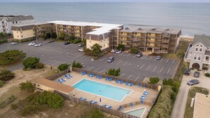 Vue aérienne d’un hôtel doté d’une piscine, de nombreux espaces de stationnement et offrant une vue sur l’océan.
