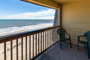 Una terraza de madera con vista a la playa y al océano.