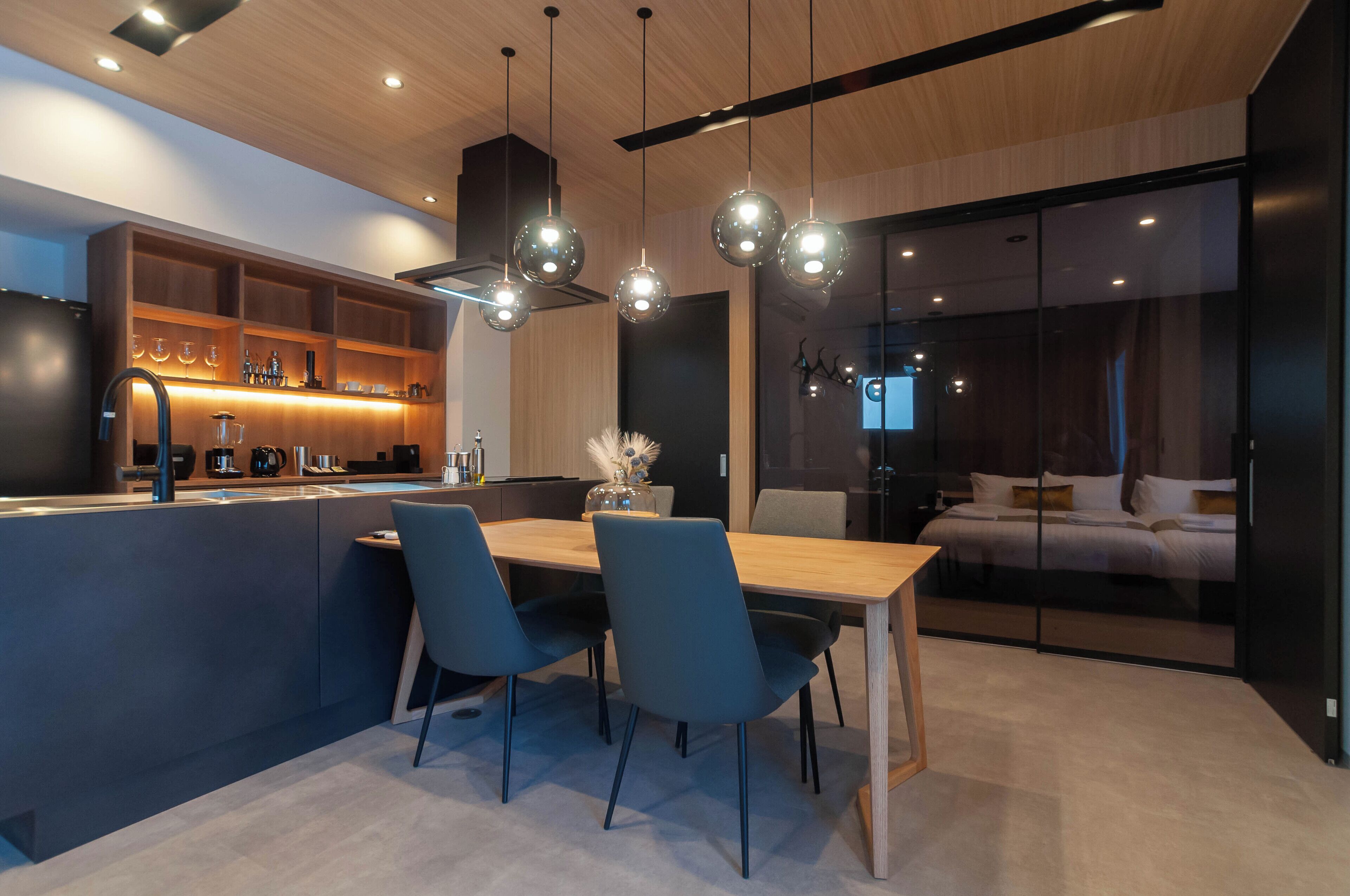 A modern kitchen with a central island, bar area, and a dining space with chairs.
