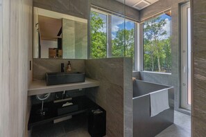 A modern bathroom with a large mirror, a sink, and a bathtub.