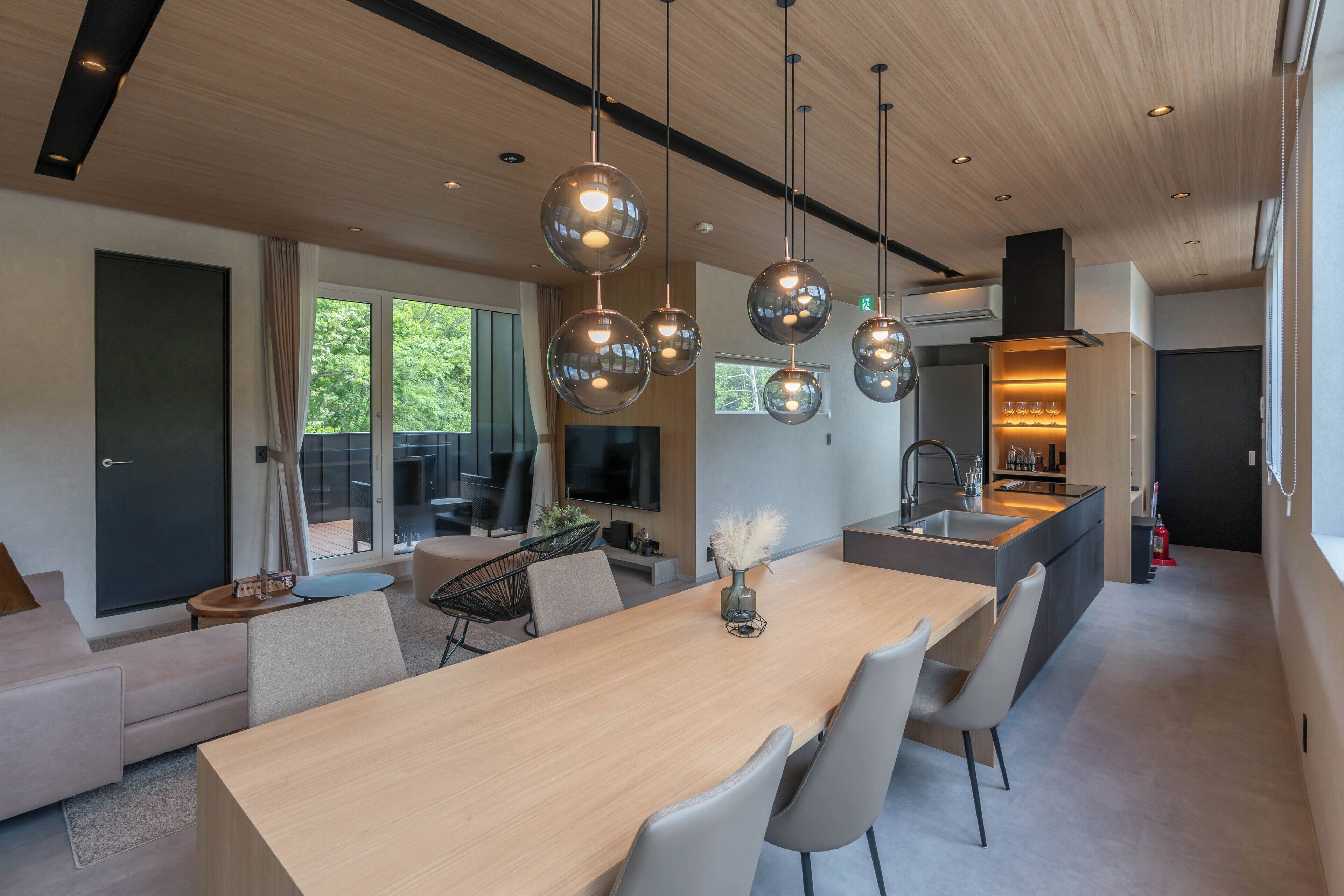 A modern kitchen with a central island, pendant lighting, and a view of the outdoors.