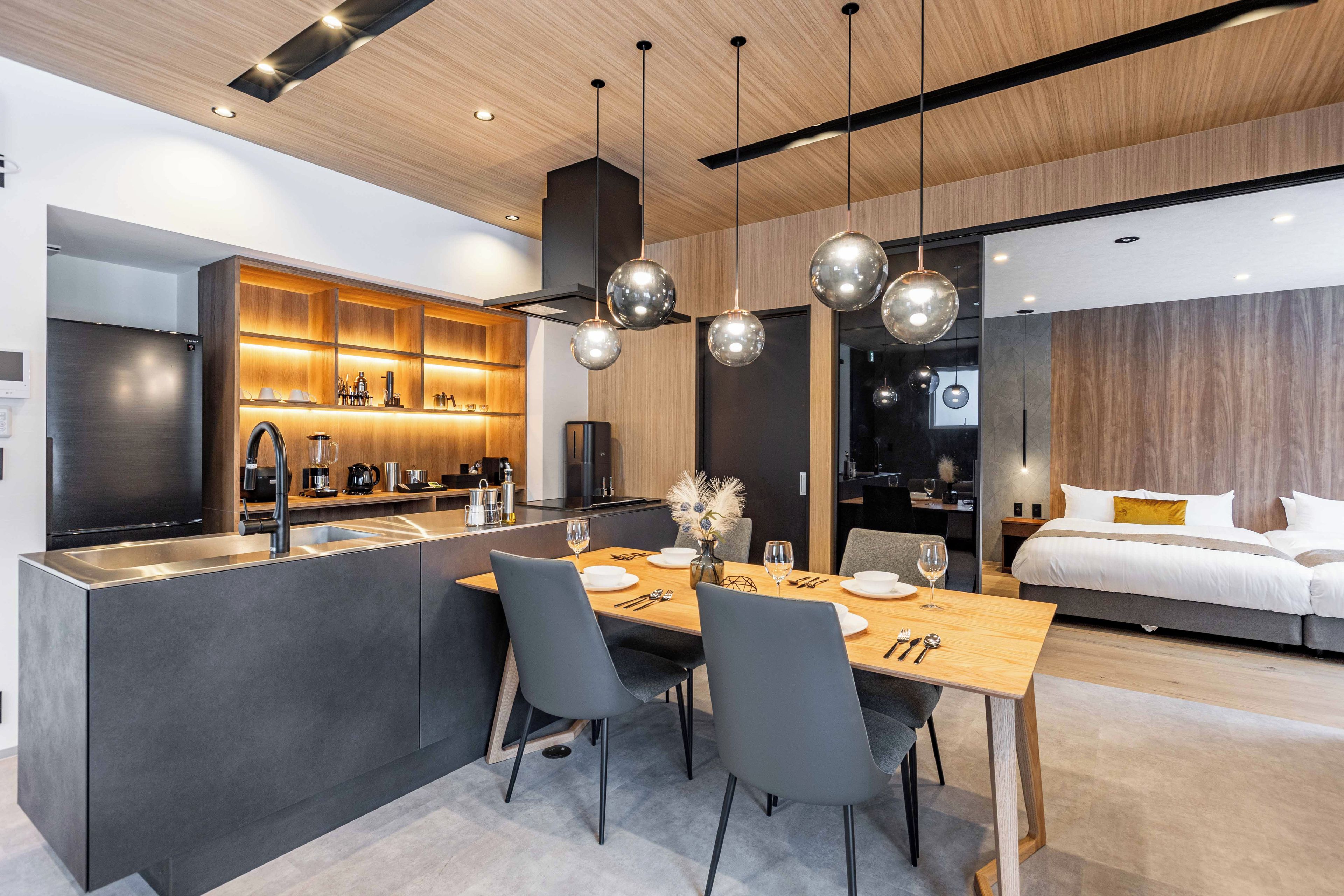 Una cocina moderna con una isla central, electrodomésticos integrados e iluminación colgante.