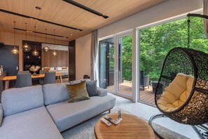 A modern living room with a grey sofa, a hanging chair, and a wooden coffee table.