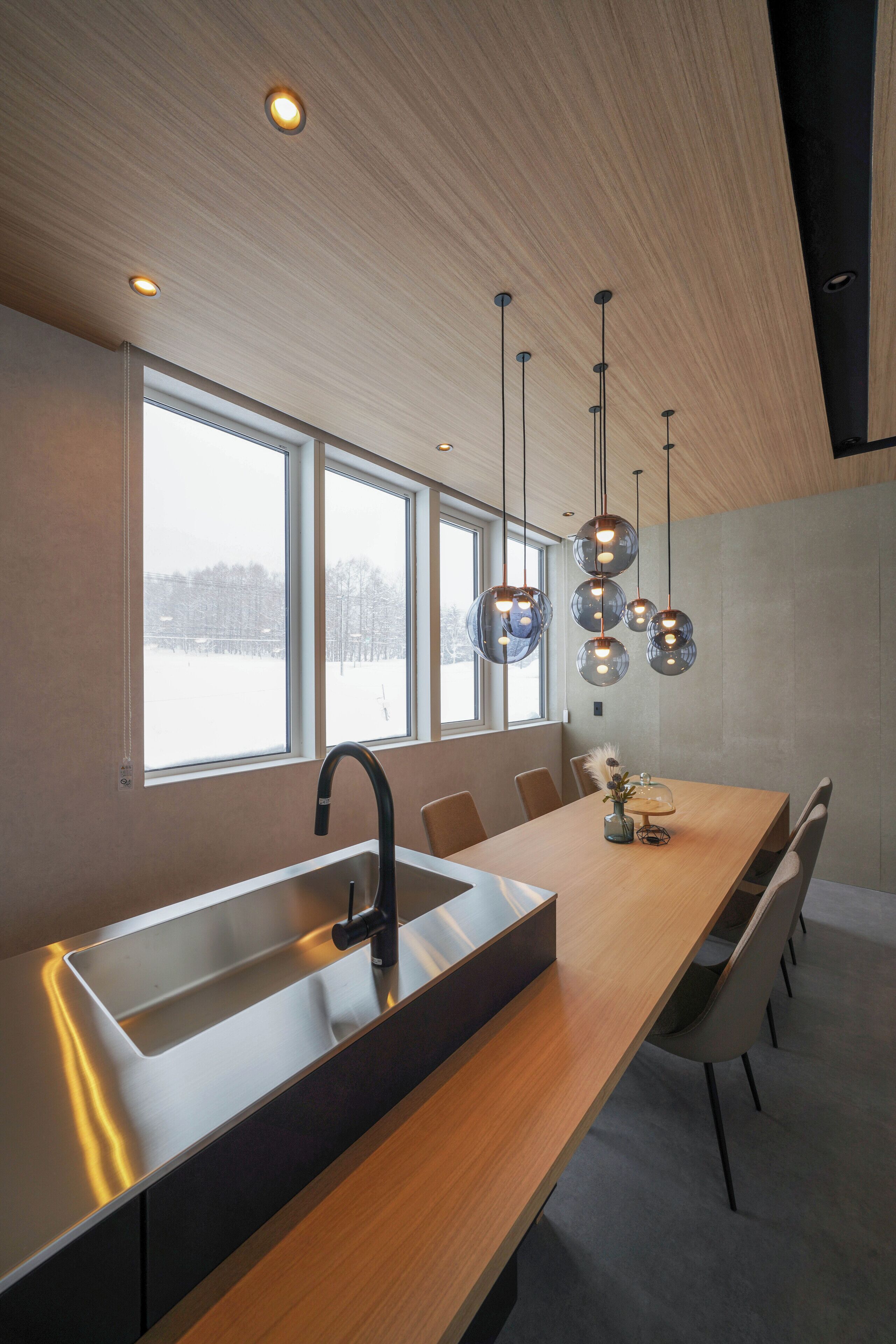 Cocina moderna con una isla grande, pileta de acero inoxidable e iluminación colgante.