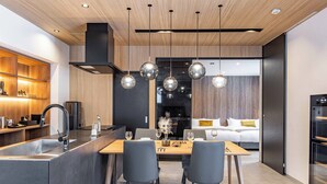 A modern kitchen with a central island, dining table, and chairs. There is a built-in oven and a large window in the background. - JAPAVISTA RUSUTSU (Rusutsu)