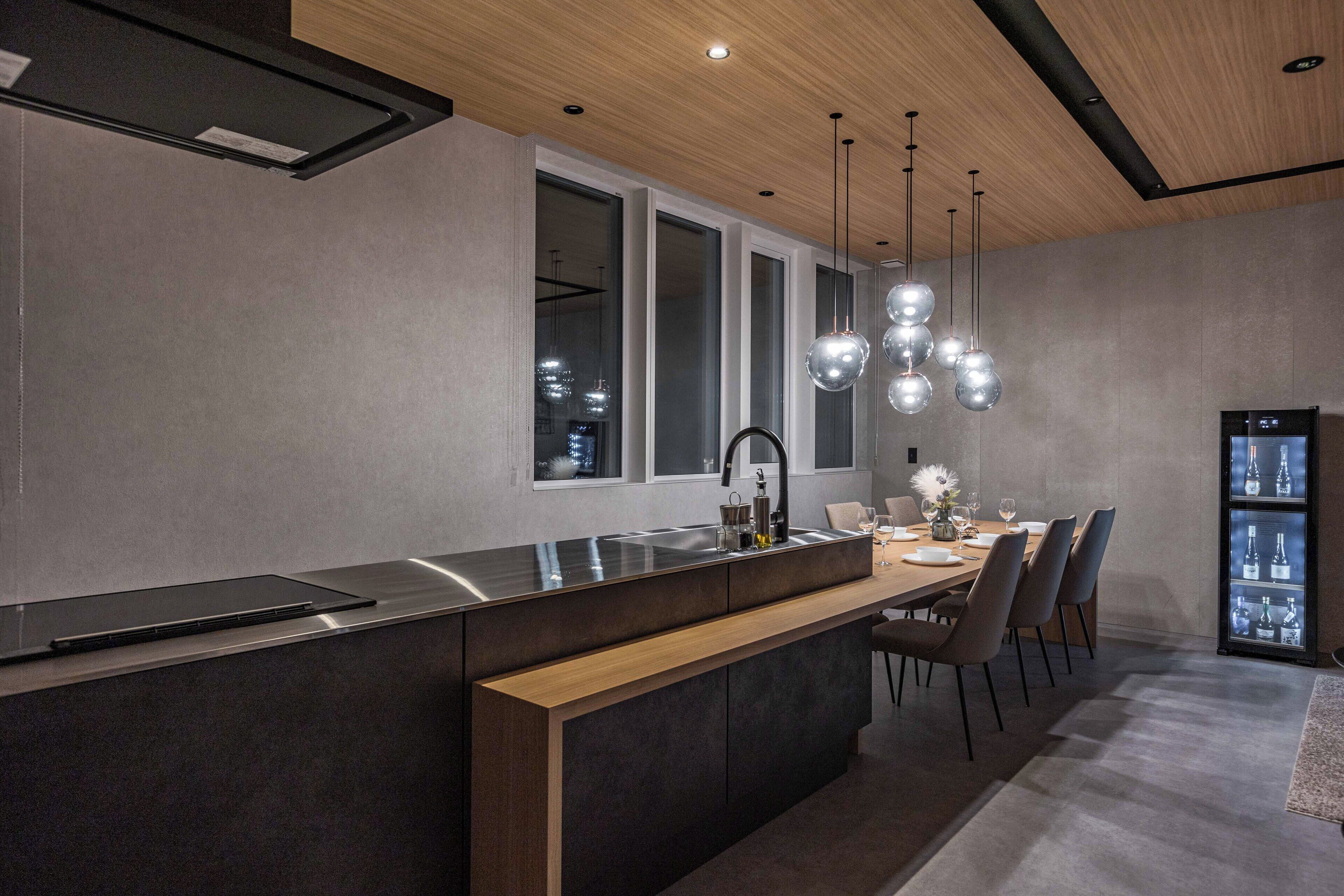 Una cocina moderna con una isla central, una zona de comedor con mesa y sillas, y un refrigerador.