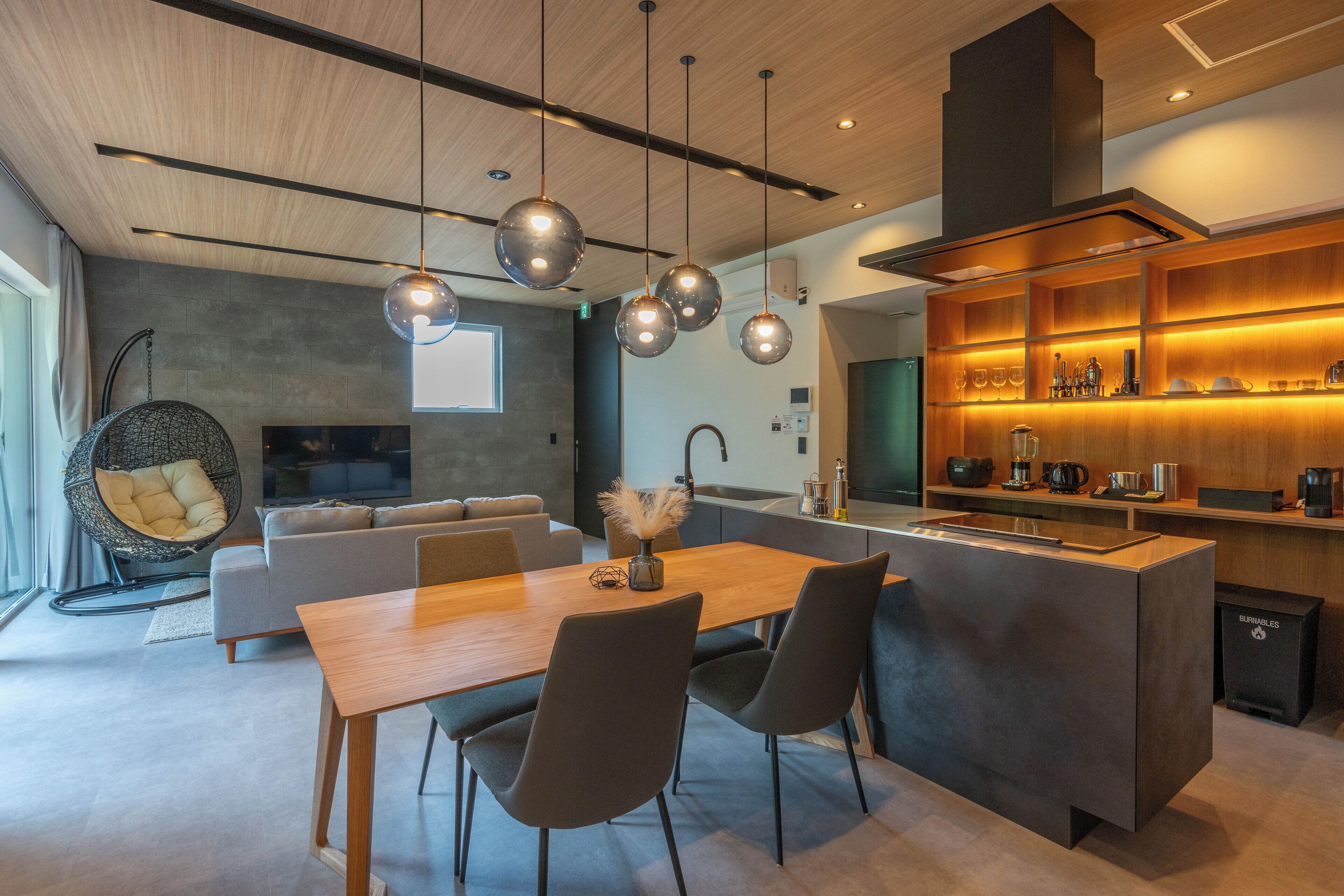 Una cocina moderna con una isla central, iluminación colgante y horno empotrado.