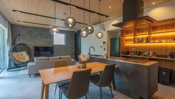 Una cocina moderna con una isla central, iluminación colgante y horno empotrado.