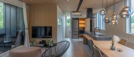 Una cocina moderna con una isla grande, iluminación colgante y un televisor de pantalla plana.