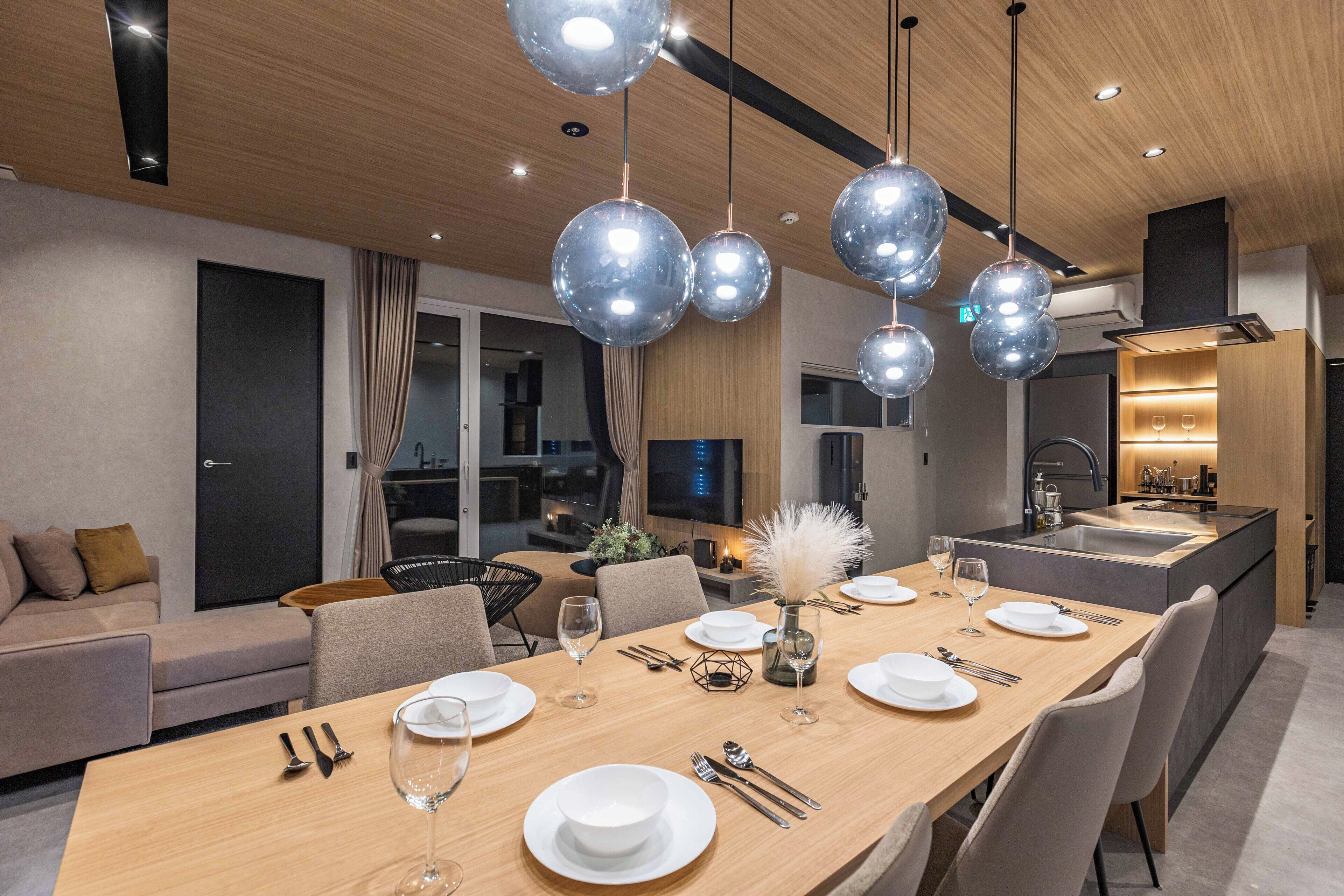 A modern dining area with a wooden table set for six, surrounded by chairs.