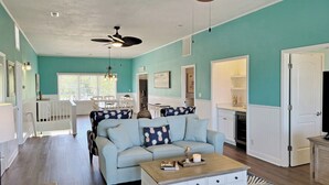A spacious living room with a light blue sofa, a wooden coffee table, and a ceiling fan. - Oceanfront House, Screen Porch, Boardwalk, Volleyball Sand Court, Game Room (Pawleys Island)