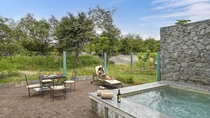 Un área de piscina con muro de piedra, sillas de descanso y una mesa con sillas.