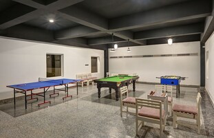 Una sala de recreación con mesa de billar, mesa de futbolín y mesas de ping pong.