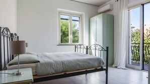A bedroom with a bed, a bedside table, a window, a wardrobe, and a balcony.