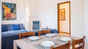 A dining area with a table set for four, a blue sofa, a chair, and two paintings on the walls.