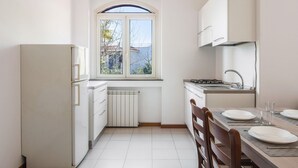 A compact kitchen with white appliances, a window, and a dining area with chairs and a table.