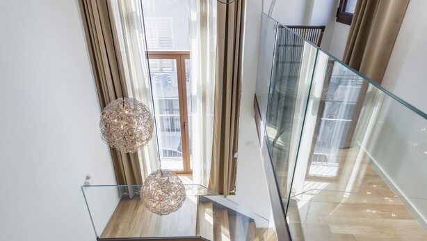 Ein modernes Interieur mit Glastrennwand, Holzboden und einer dekorativen, kugelförmigen Leuchte.