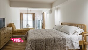 Ein Schlafzimmer mit einem Bett, einer hölzernen Kommode, einem Fernseher und einem Fenster mit Vorhängen.