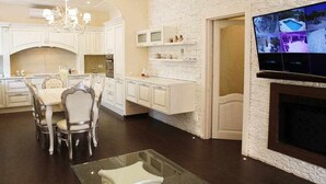A modern kitchen with white cabinetry, a dining area with a glass table, and a fireplace. - Luxury Vale Villa. (Locorotondo)